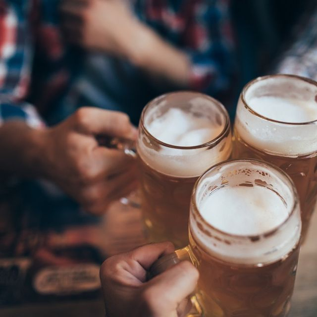 manos de jovenes brintando con tres jarras de cerveza